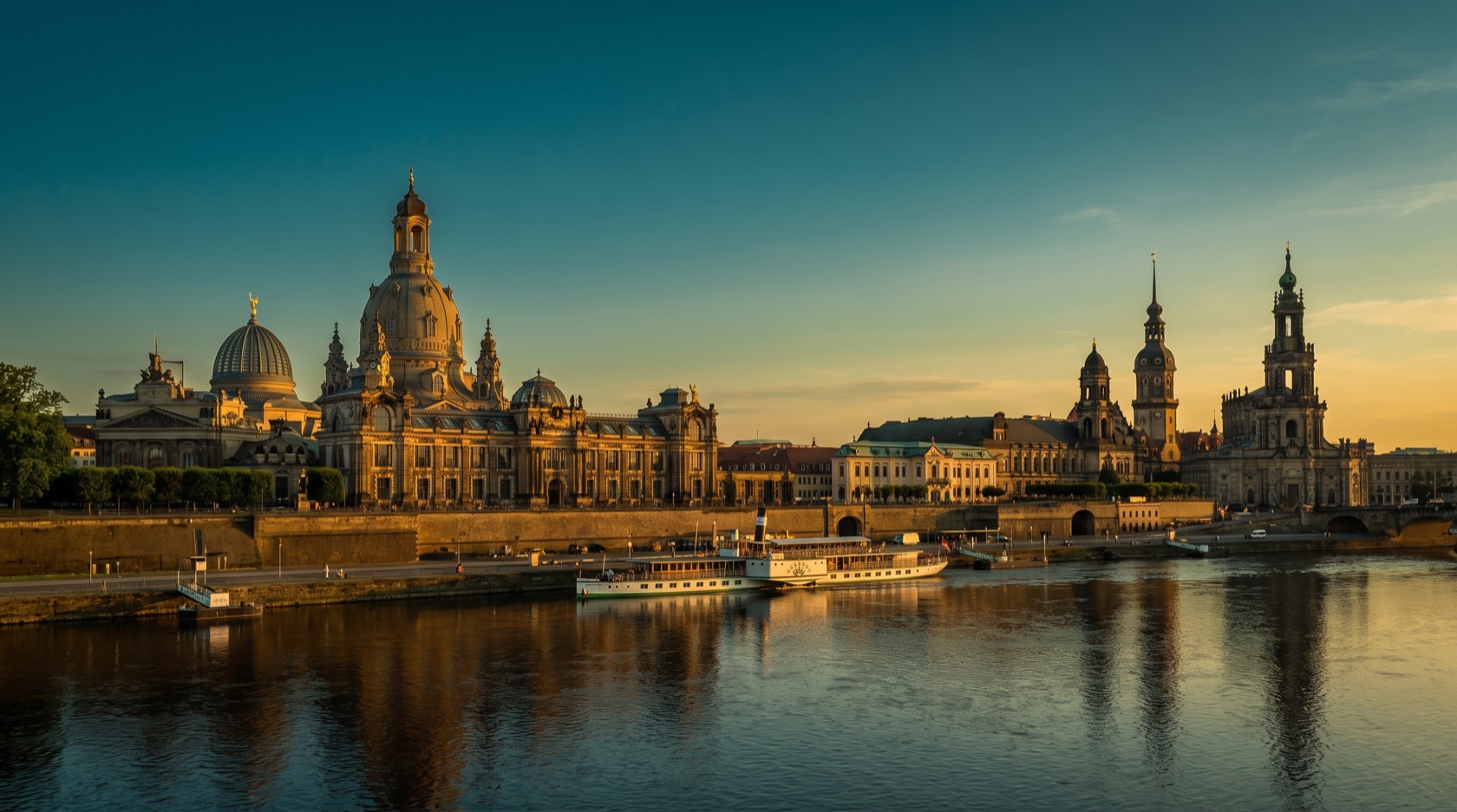 Dresden an der Elbe im Abendlicht: die Kuppel der Frauenkirche, die Semperoper und der Zwinger als barocke Silhouette